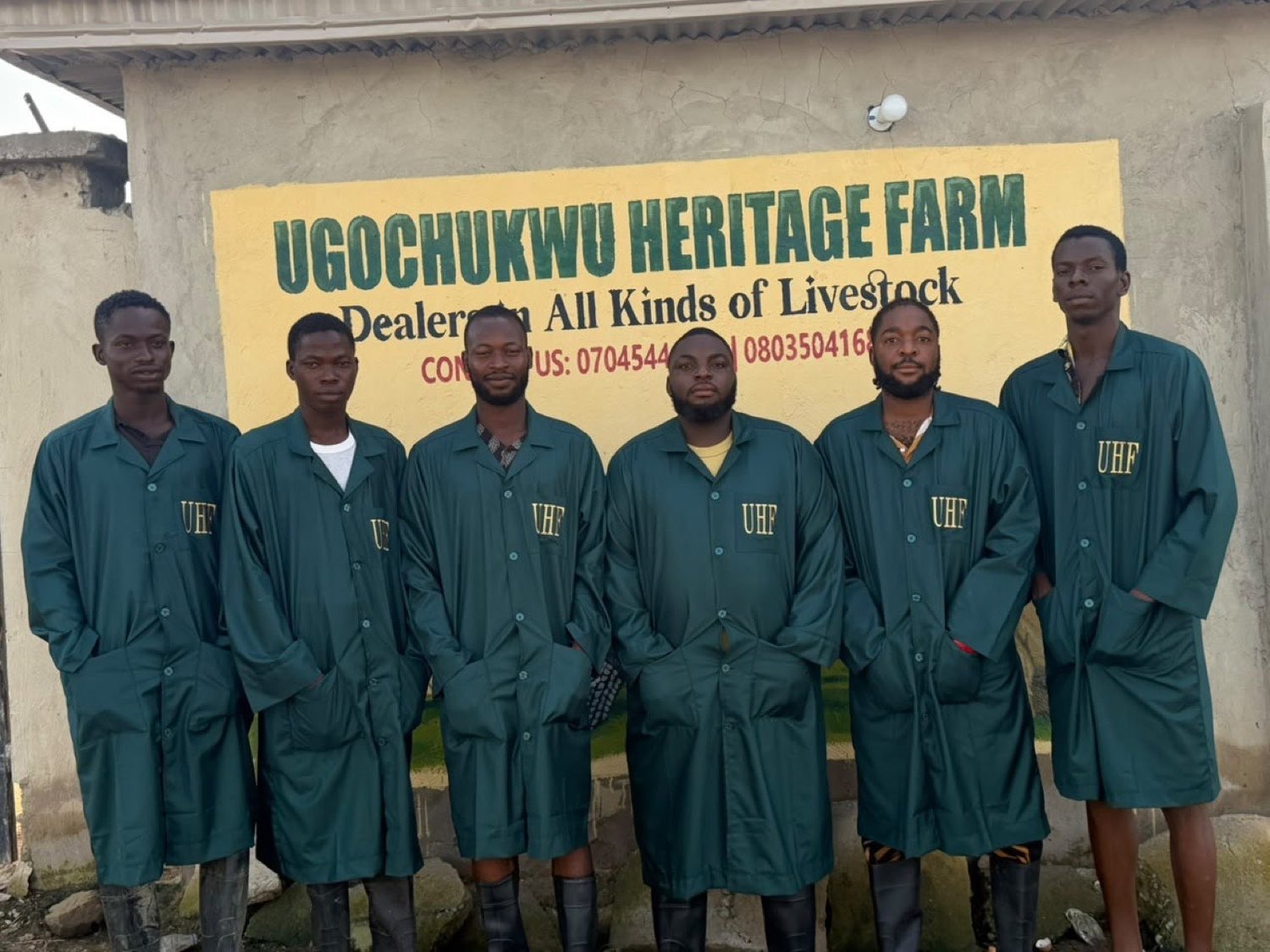 The Ugo Heritage Farm team in branded coveralls at the farm signboard
